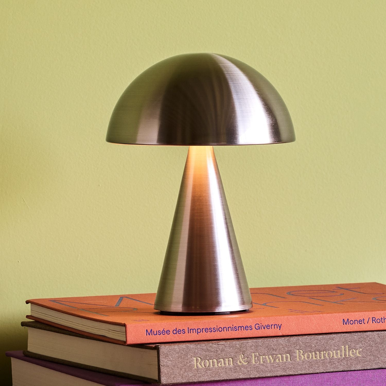 Tragbare Lampe in nickel auf einem bunten Bücherturm