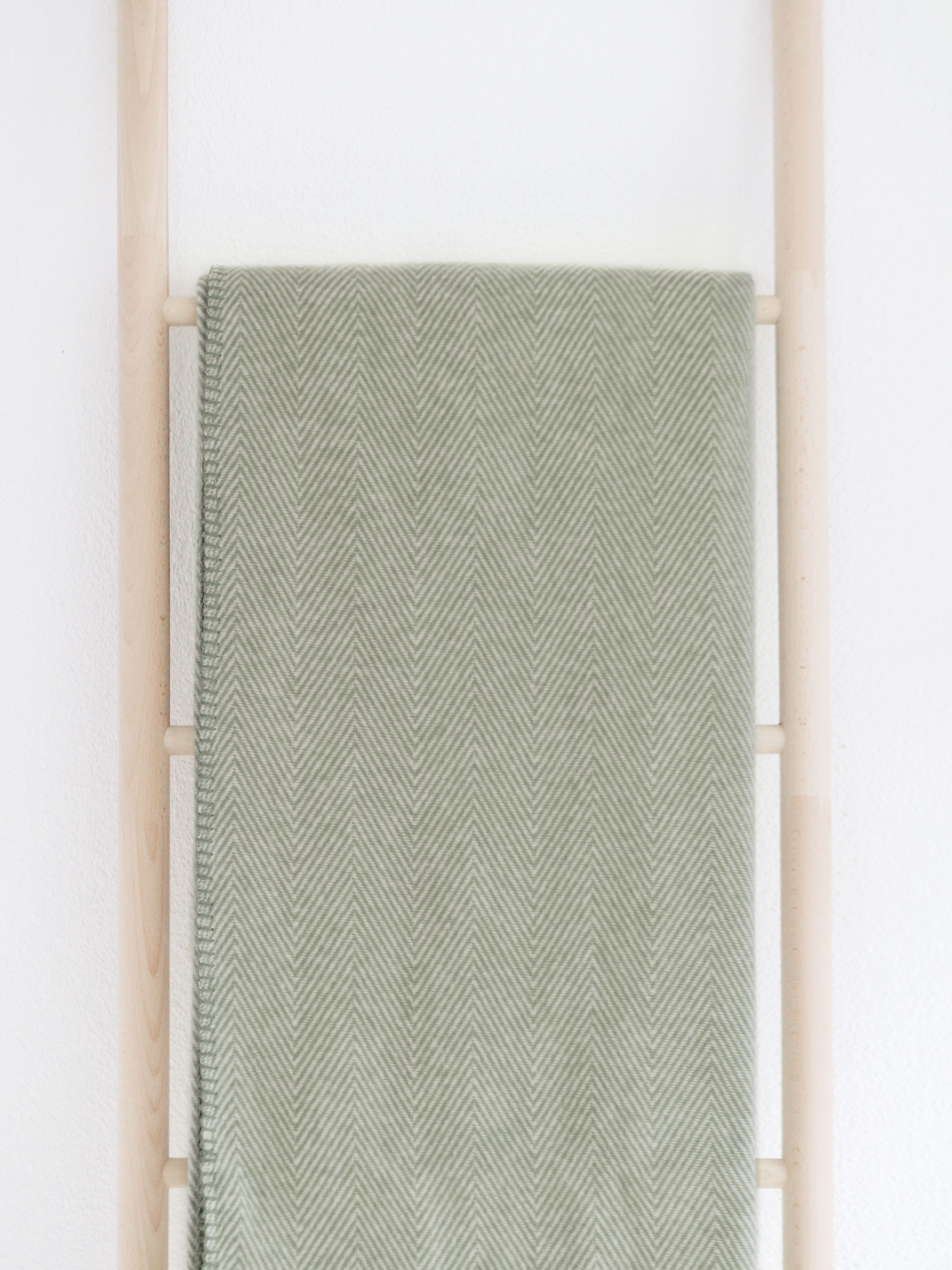 riema germany kuscheldecke finn grün aus bio baumwolle mit fischgrätmuster auf holzleiter