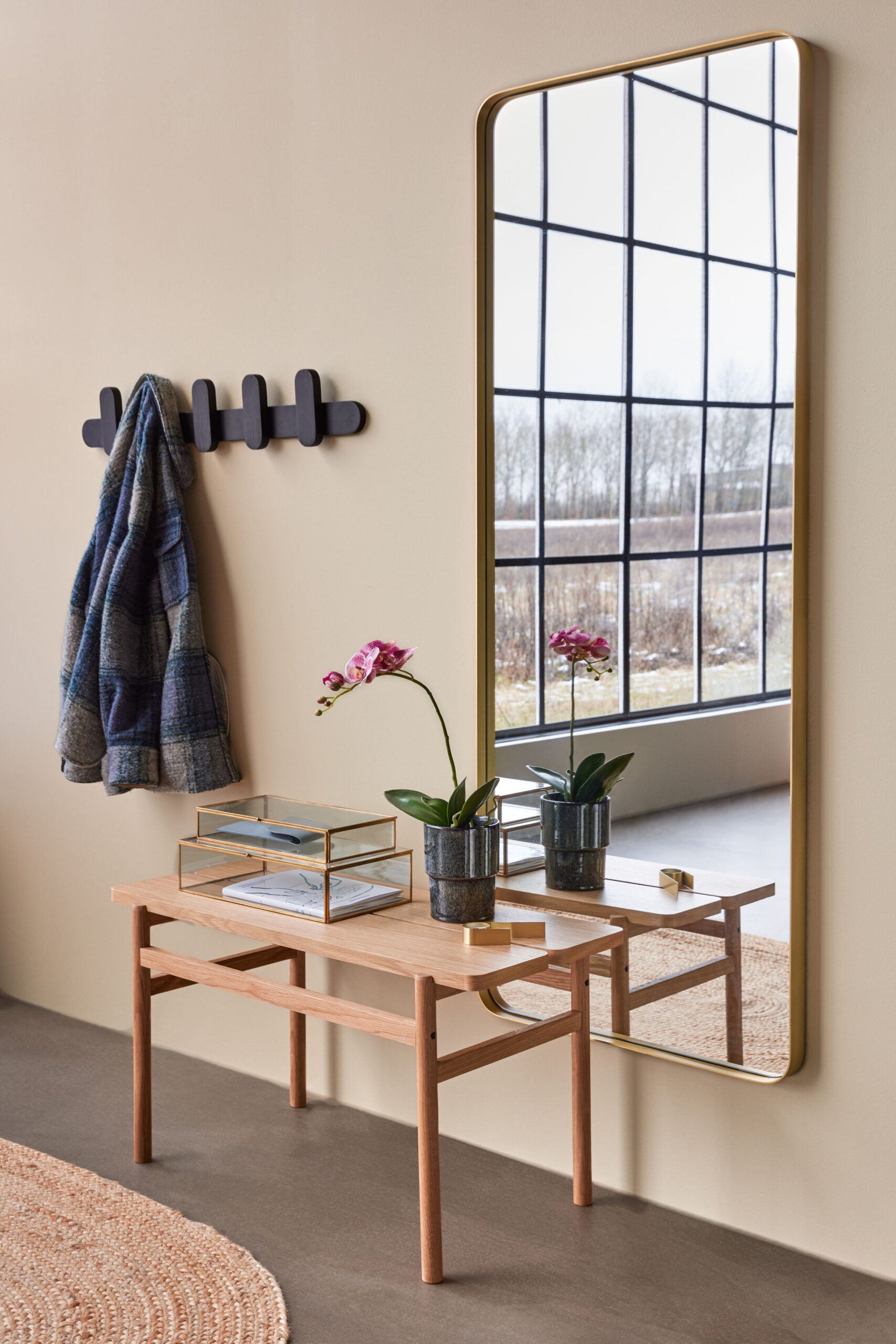 dunkelgrüner keramikübertopf mit strukturierter glasur auf einem tisch vor einem spiegel im flur