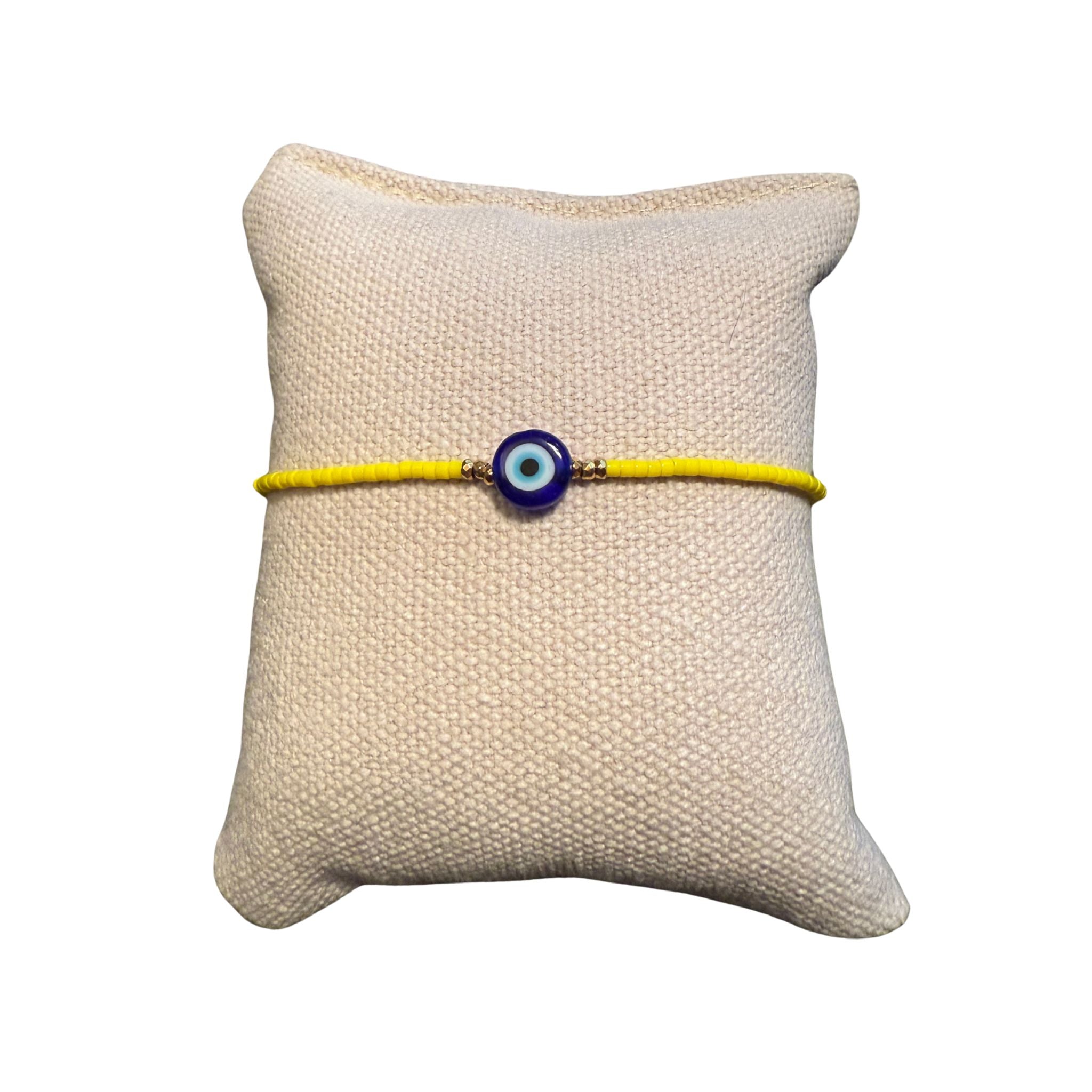 Gelbes Glasperlenarmband auf einem Stoffkissen