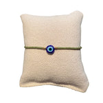 Gruenes Glasperlenarmband auf einem Stoffkissen.