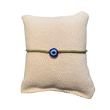 Gruenes Glasperlenarmband auf einem Stoffkissen.