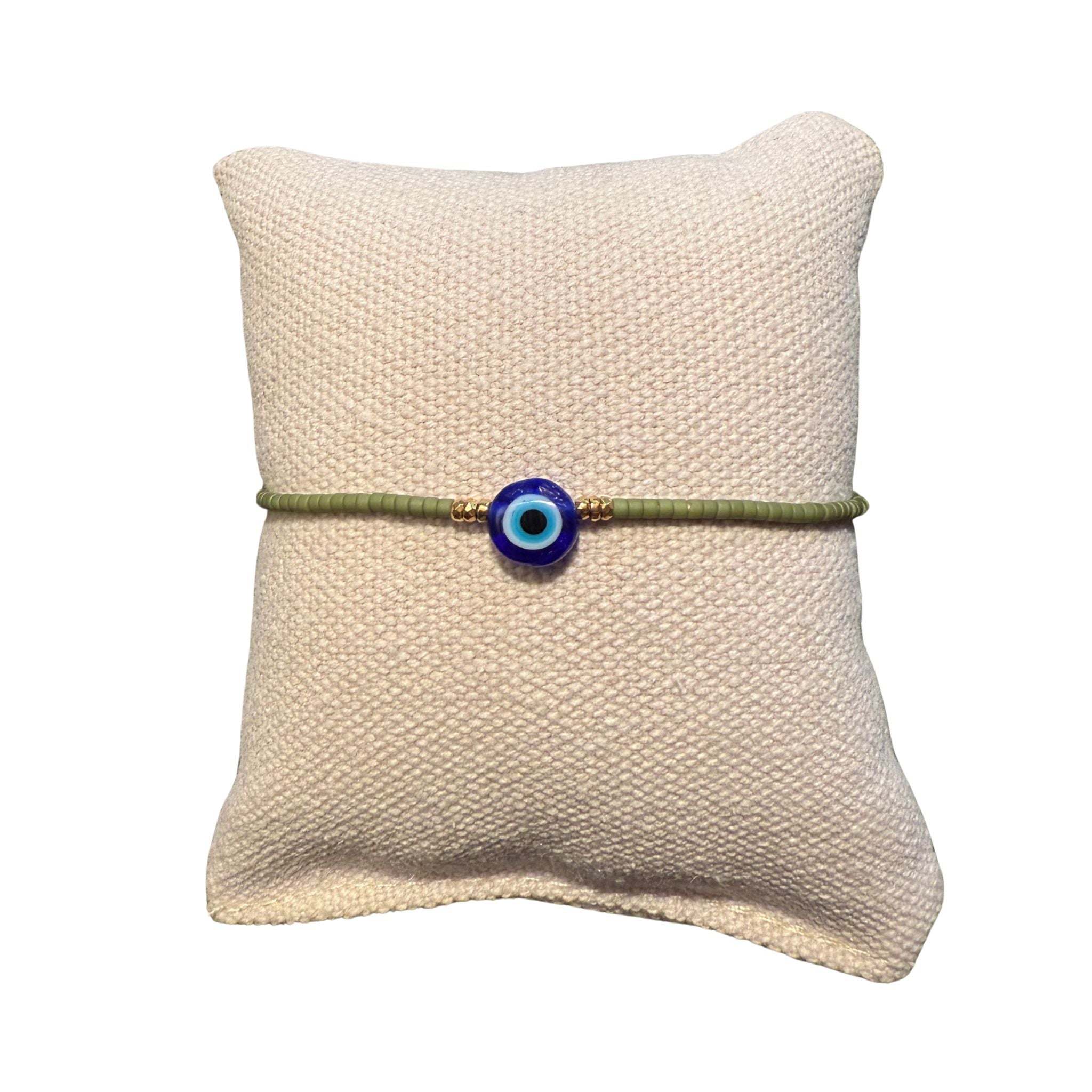 Gruenes Glasperlenarmband auf einem Stoffkissen.