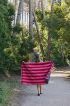 Frau mit tores nova badetuch gruen rosa und rot rosa auf einem waldweg