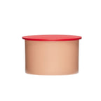 Kleine Metalldose in rosa mit rotem Deckel.