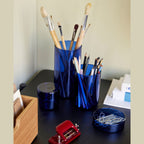 Pop Aufbewahrungslaeser von Huebsch in blau auf einem Schreibtisch mit Stiften und Pinseln gefüllt.