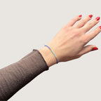 Zweifarbiges Perlenarmband in blau und hellblau getrennt duch jeweils drei goldene Perlen. Gezeigt an einem Handgelenk.