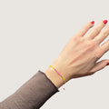 Zweifarbiges Perlenarmband in gelb und pink getrennt durch jeweils drei goldene Perlen. Gezeigt an einem Handgelenk.