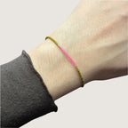 Zweifarbiges Perlenarmband in gelb und pink getrennt durch jeweils drei goldene Perlen. Gezeigt an einem Handgelenk.