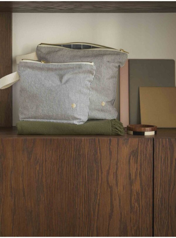 zwei schwarz-weiss gestreifte kulturbeutel aus baumwolle dekorativ im regal platziert