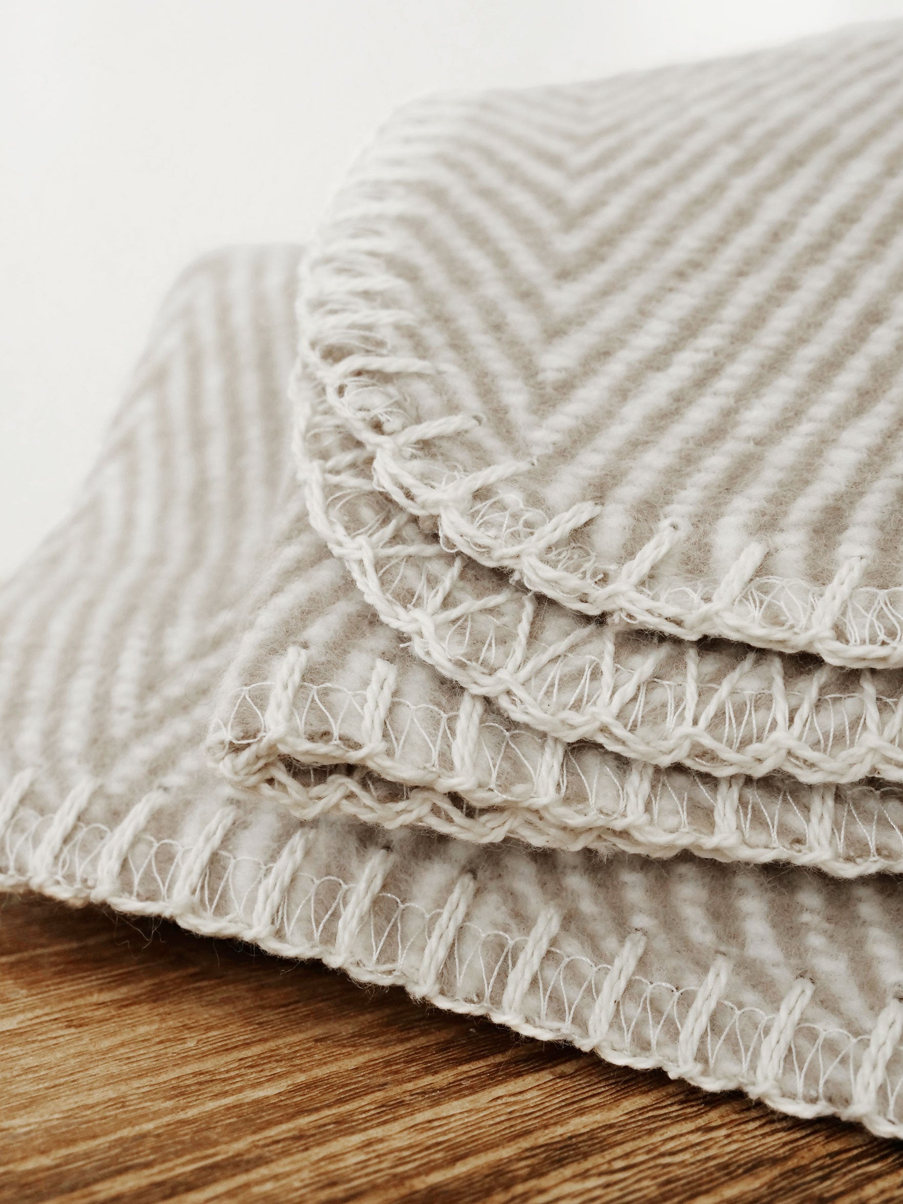 Nahaufnahme einer taupefarbenen Baumwolldecke mit Fischgrätmuster 