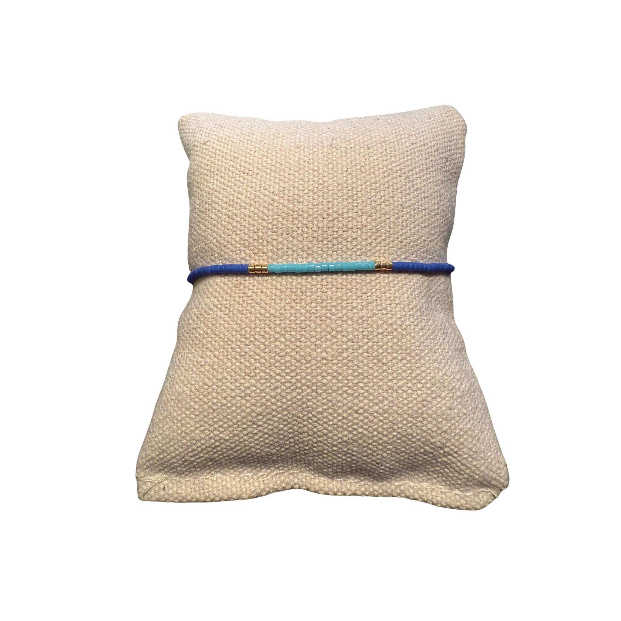 Zweifarbiges Perlenarmband in blau und hellblau getrennt duch jeweils drei goldene Perlen.