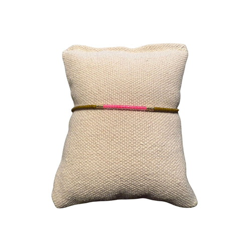 Perlenarmband auf einem beigen Stoffkissen.