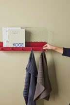 blaues und braunes geschirrtuch mit feinen streifen aus baumwolle an wandhaken im skandinavischen stil