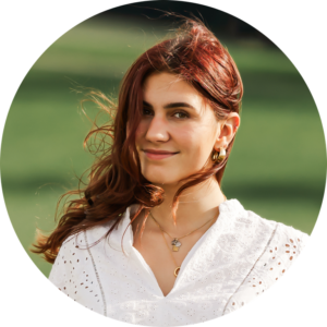 portraitfoto von catalina mit langen braunen haaren und weißer bluse draußen im grünen
