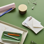 Kleine braune Metaldose auf gruenem Tisch mit Karten und Briefumschlaegen