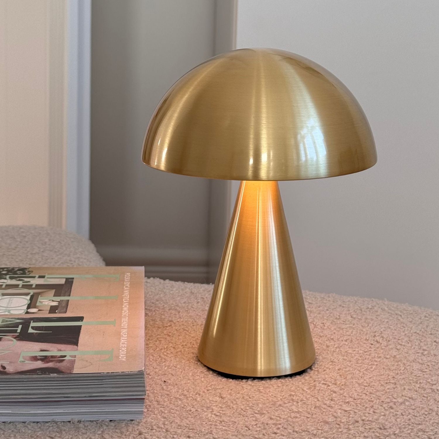 Messingfarbene Lampe auf Tisch neben Zeitschriften