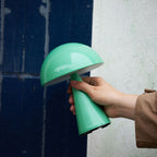 Frauenhand hält eine kleine Lampe vor blauer Hauswand