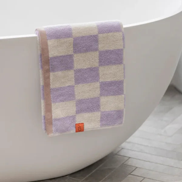 mette ditmer gästehandtuch retro muster flieder aus 100% bio-baumwolle drapiert über badewanne
