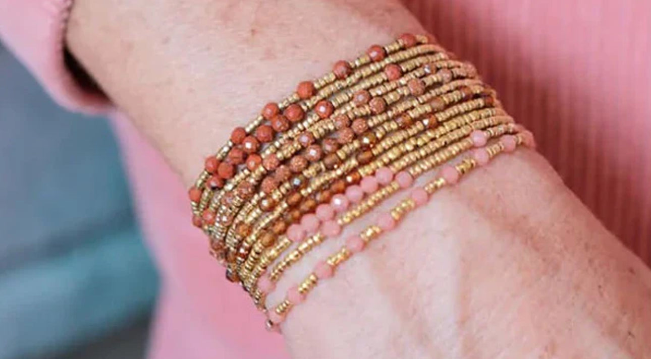 Mehrreihige Sabelline Armbänder in Gold und Rosa am Handgelenk auf rosa Jacke