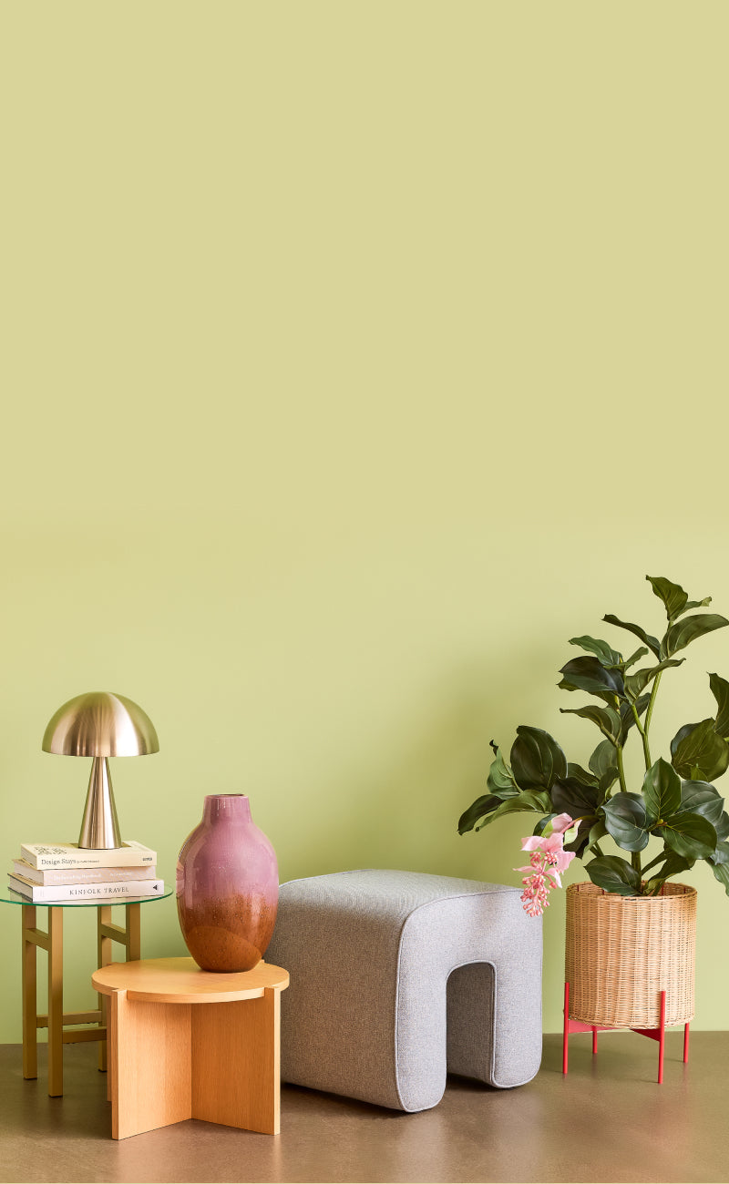 Zwei Beistelltische dekorert mit Vase und Tischlampe, Textilhocker, Blumenübertopf aus Rattan.