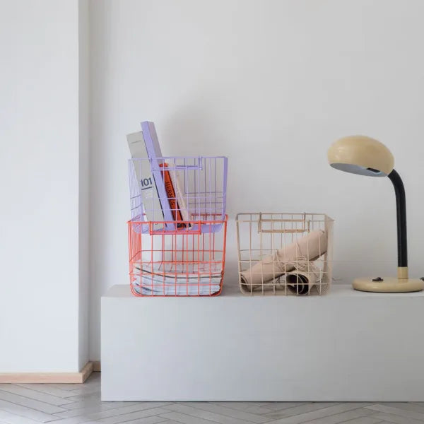 drei drahtkörbe in sand orange und lila mit zeitschriften und buechern gefuellt und eine tischlampe